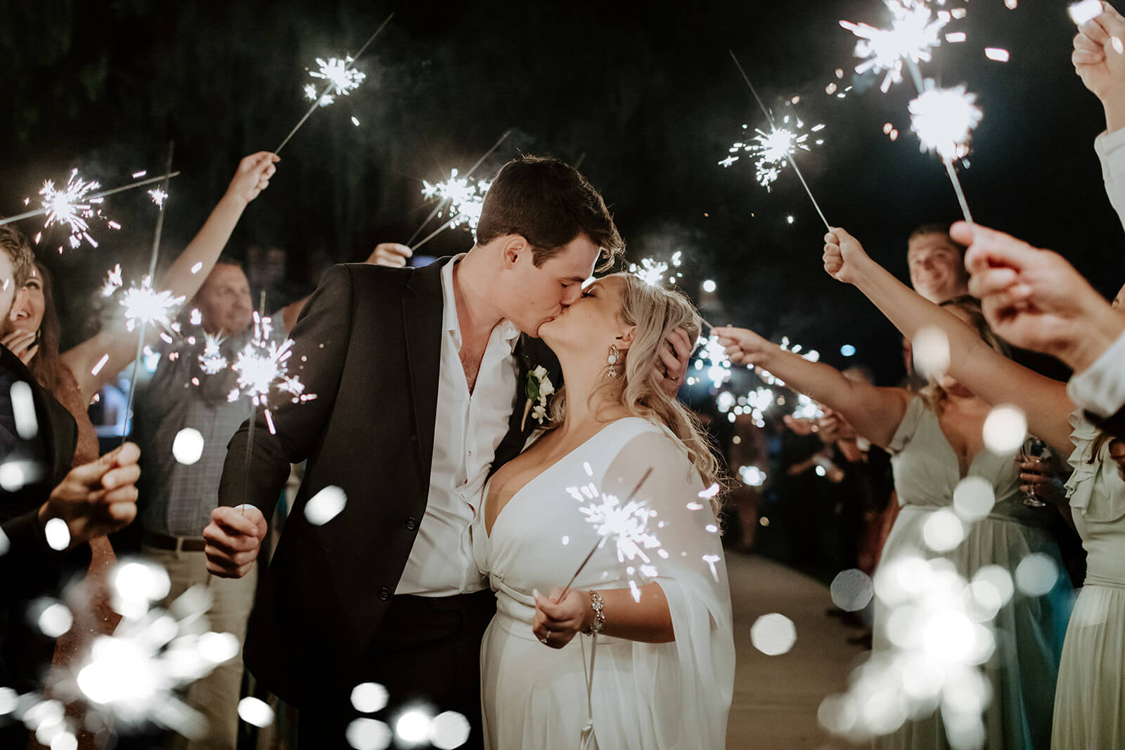 bride and groom kiss while holding sparklers