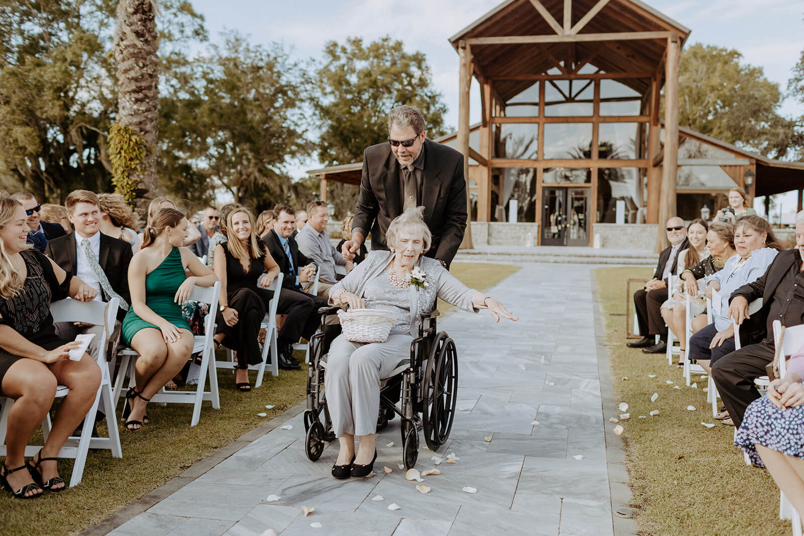 lady in wheelchair throws flowers down wedding aisle