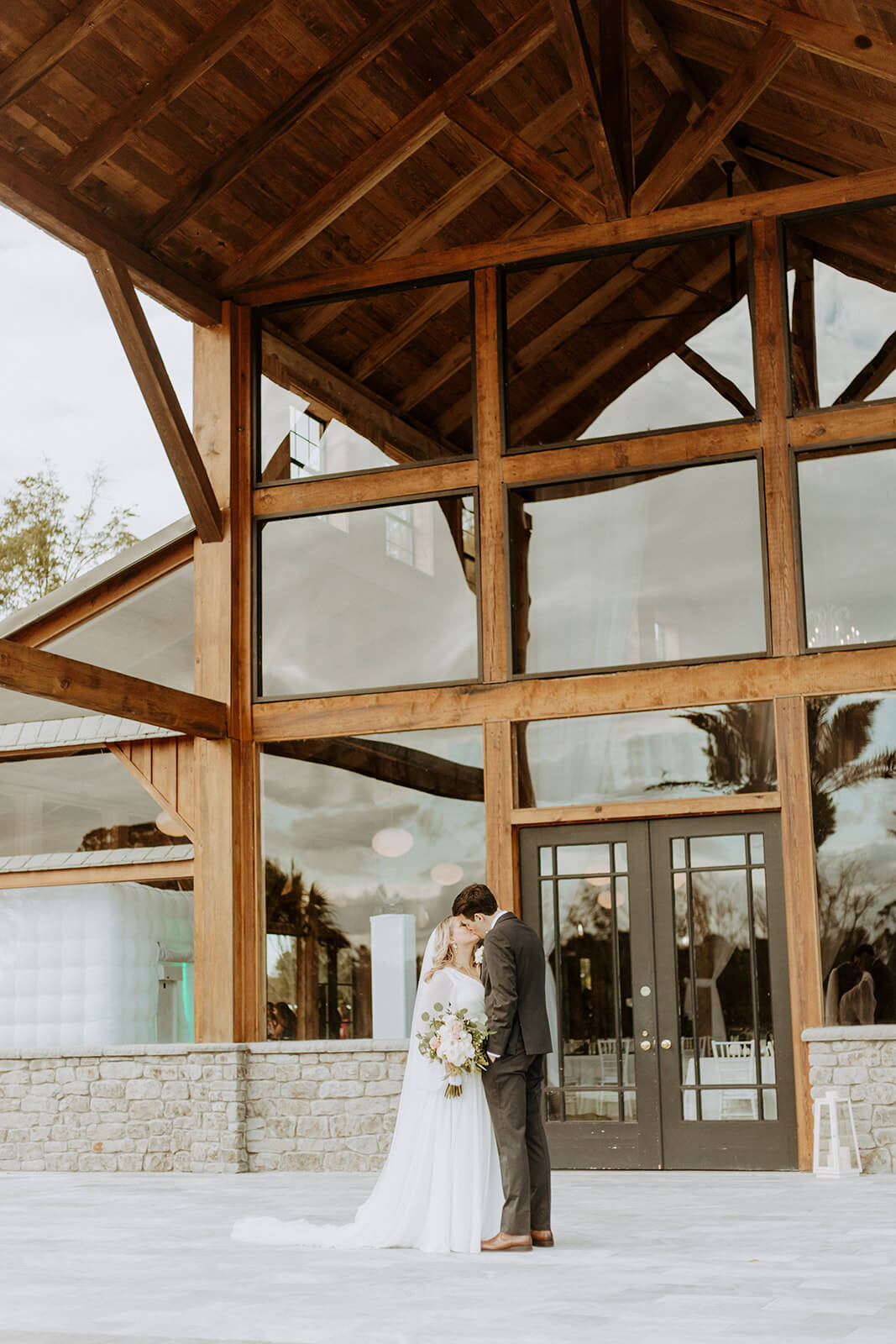 bride and groom kiss in front of barn