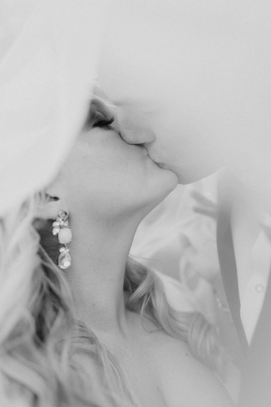 bride and groom kiss under veil