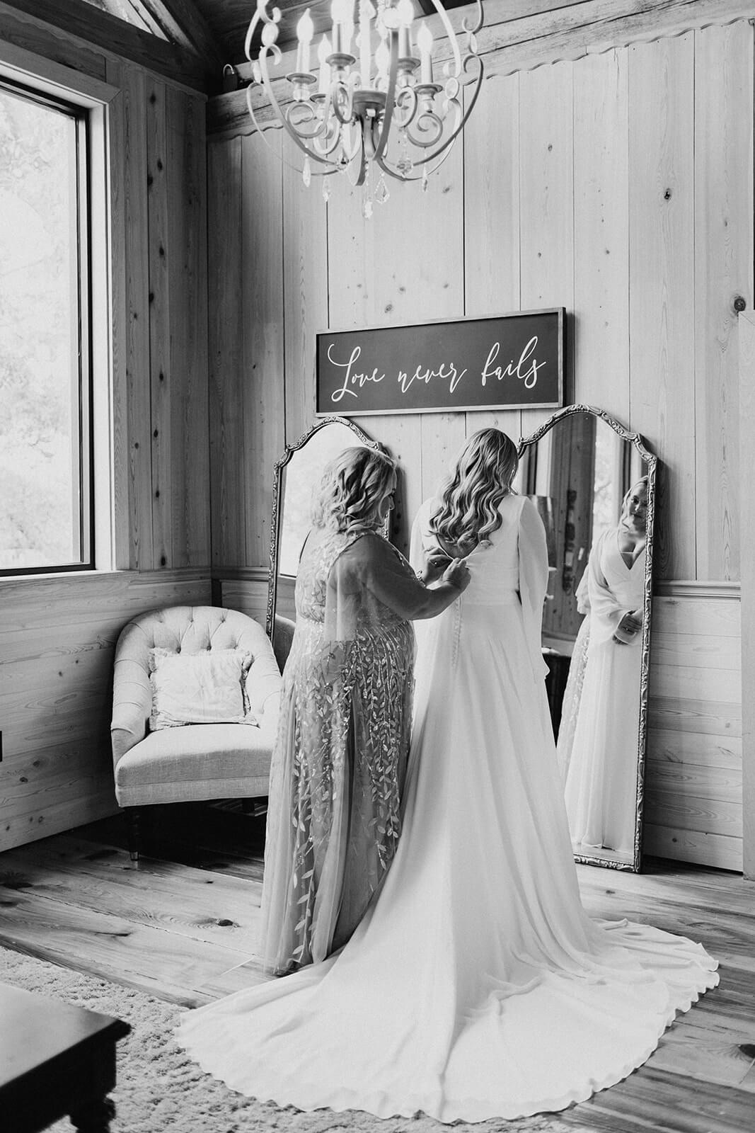 bride putting dress on in front of large mirror
