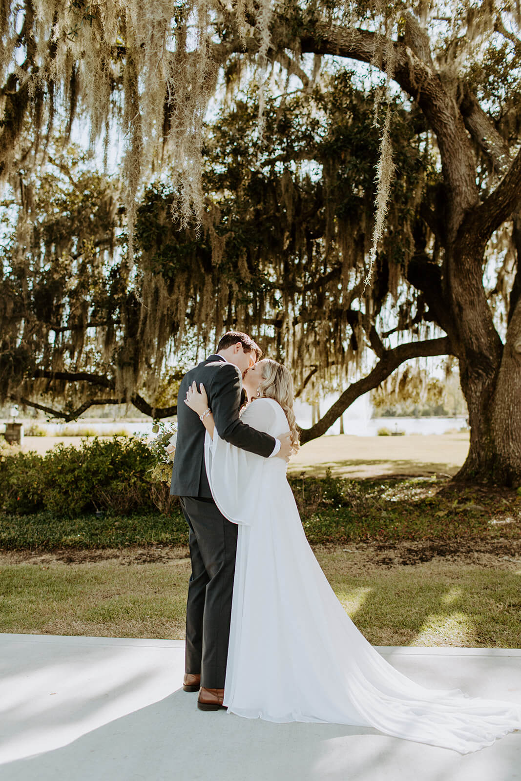 man and woman kiss in front of large tree at the barn at cottonwood ranch