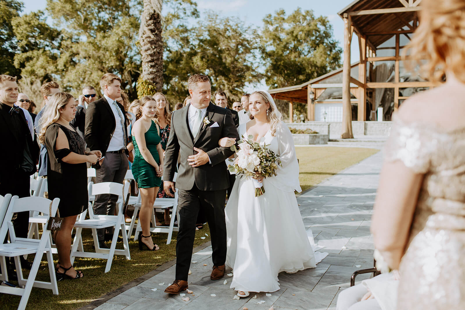 bride walks down aisle in with father in front of cottonwood ranch