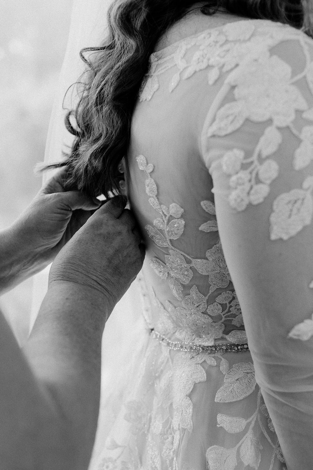 close up image of hands zipping wedding dress