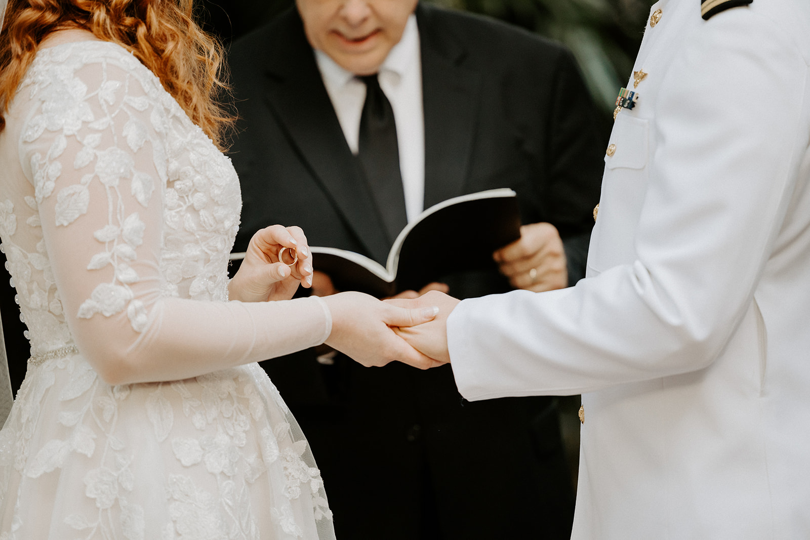 close up image of bride putting wedding ring on groom