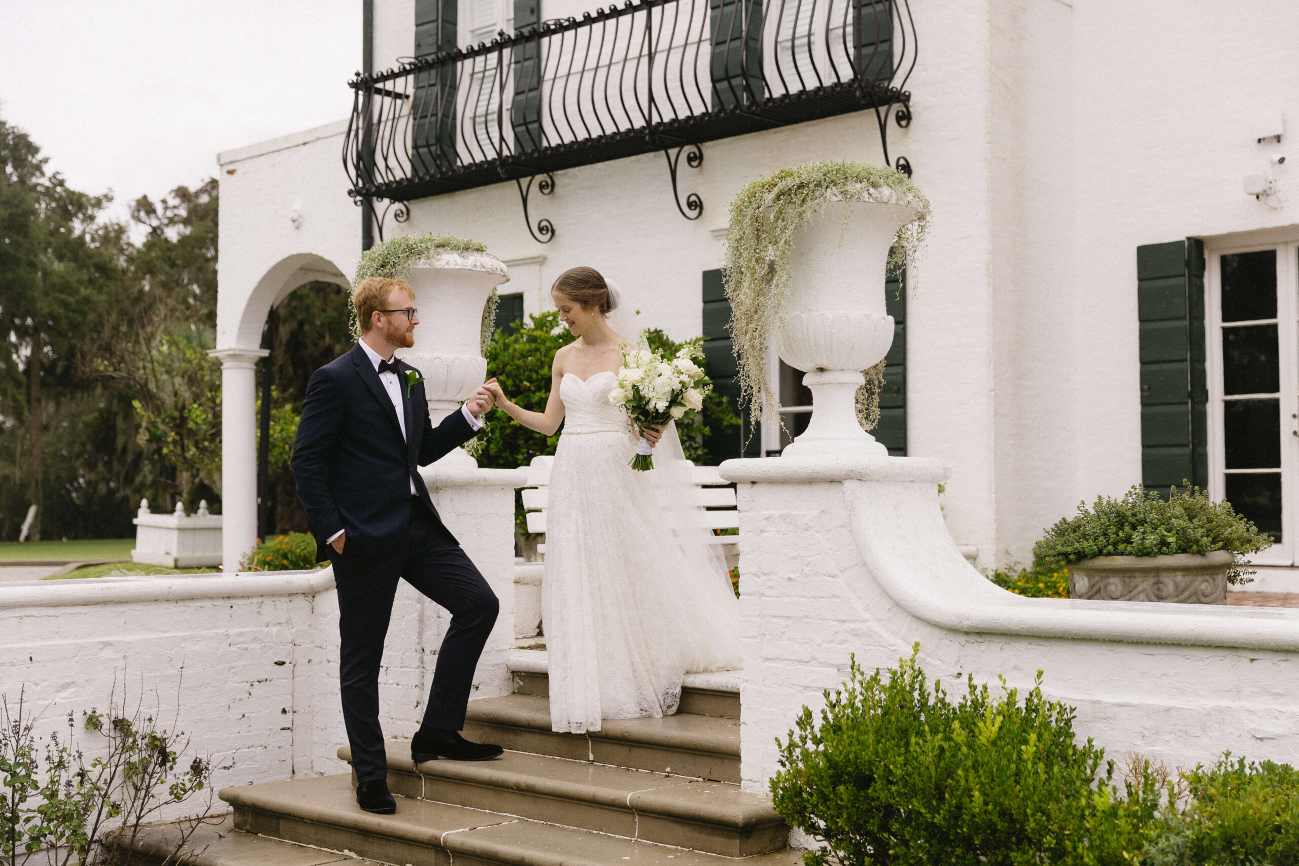 groom helps bride down stairs at crane cottage wedding