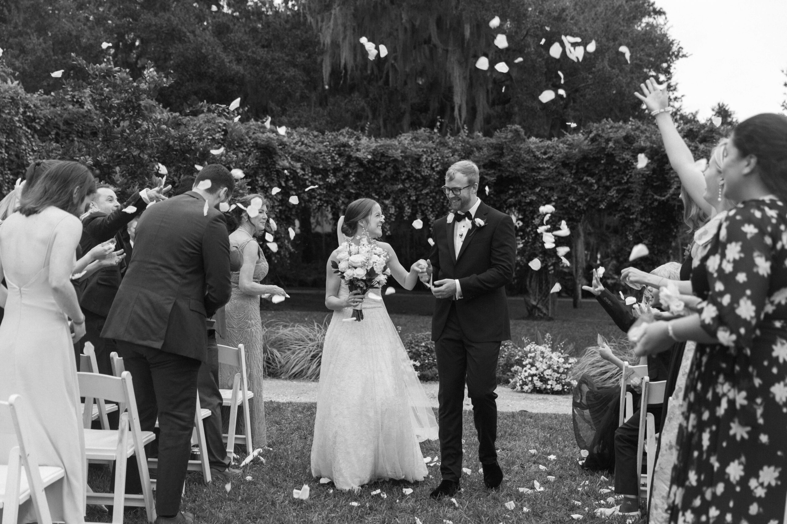bride and groom walk hand in hand and smile down aisle