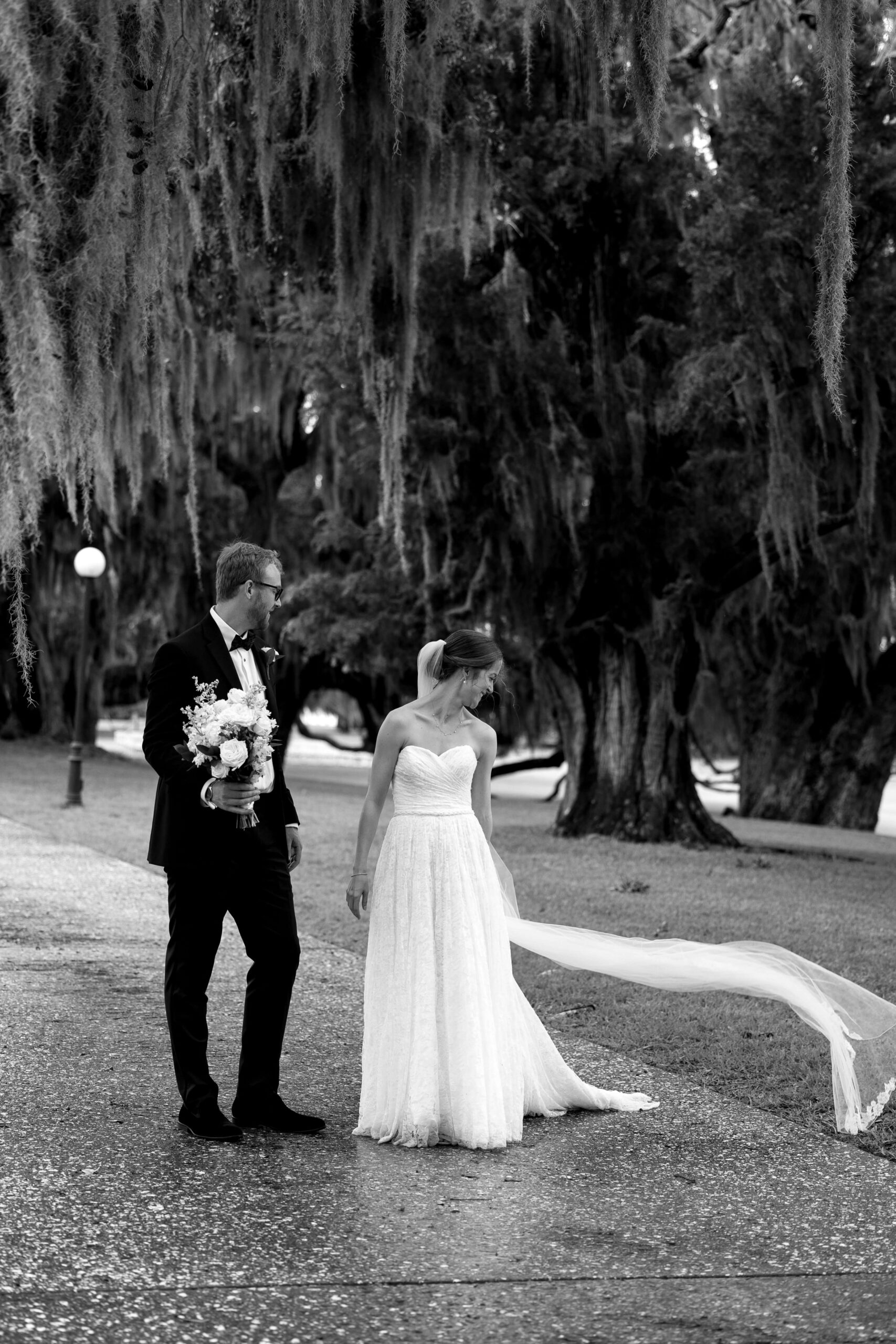 bride and groom stand together under oak trees