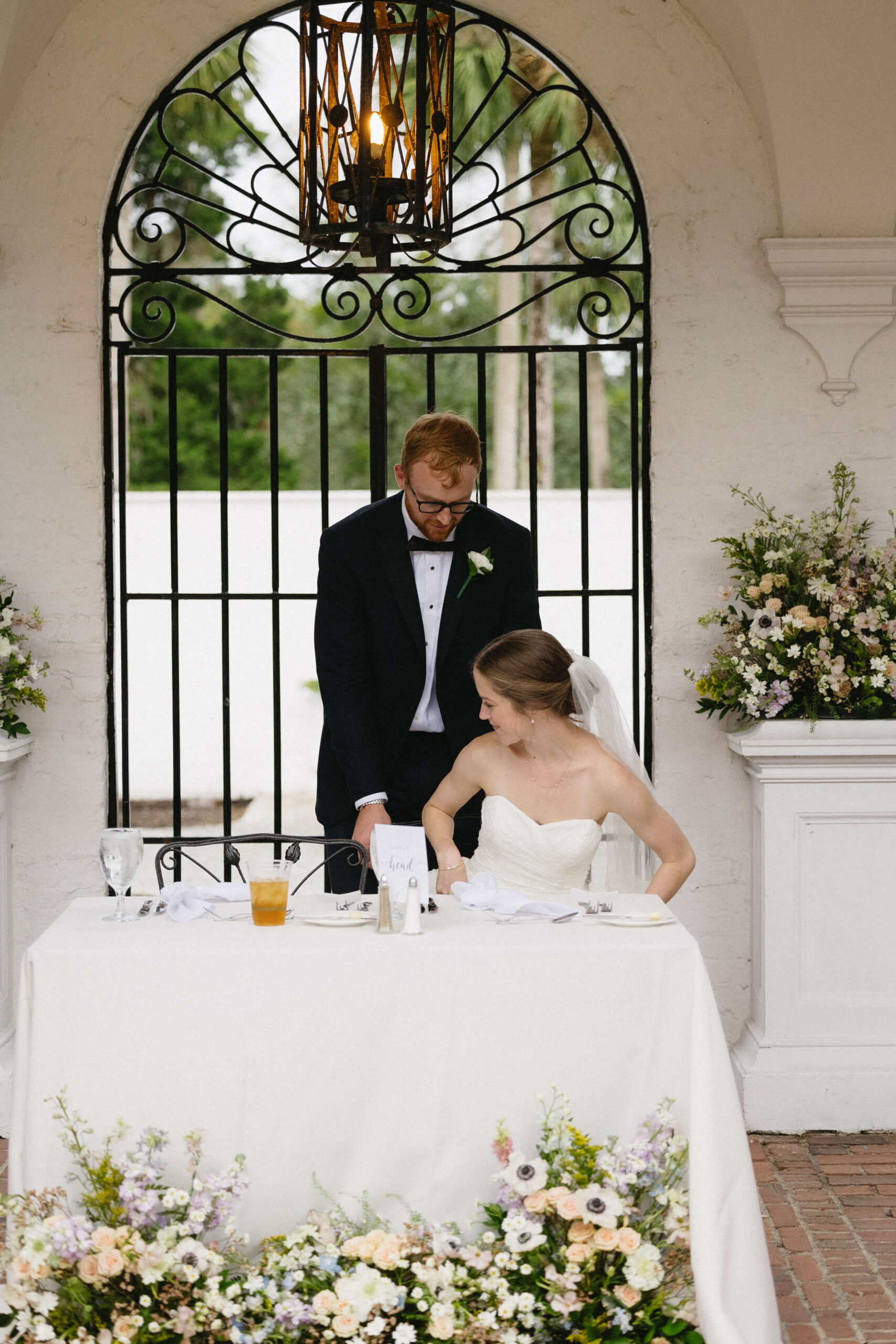groom helps bride sit down at wedding reception