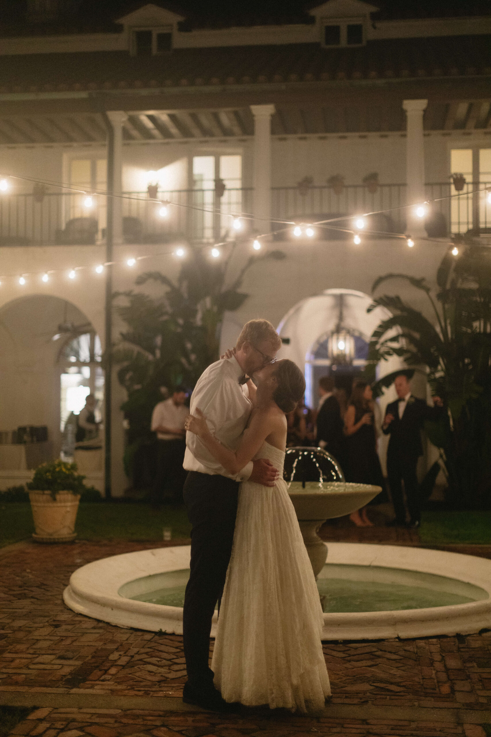 bride and groom kiss in courtyard of wedding reception at crane cottage