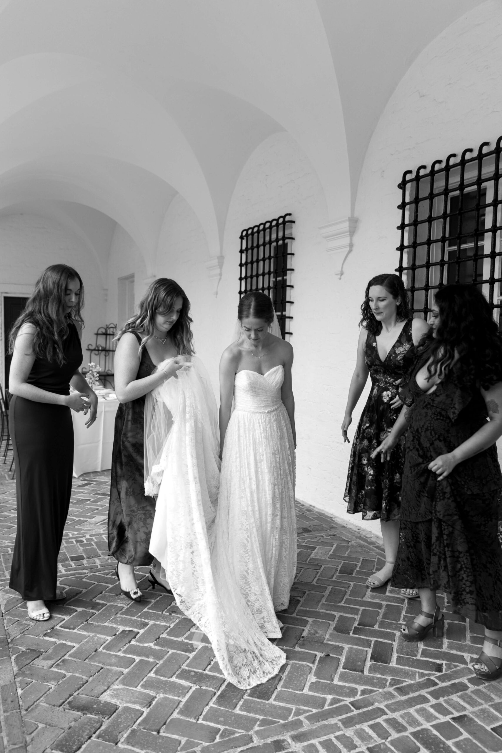 four women helping bride with dress