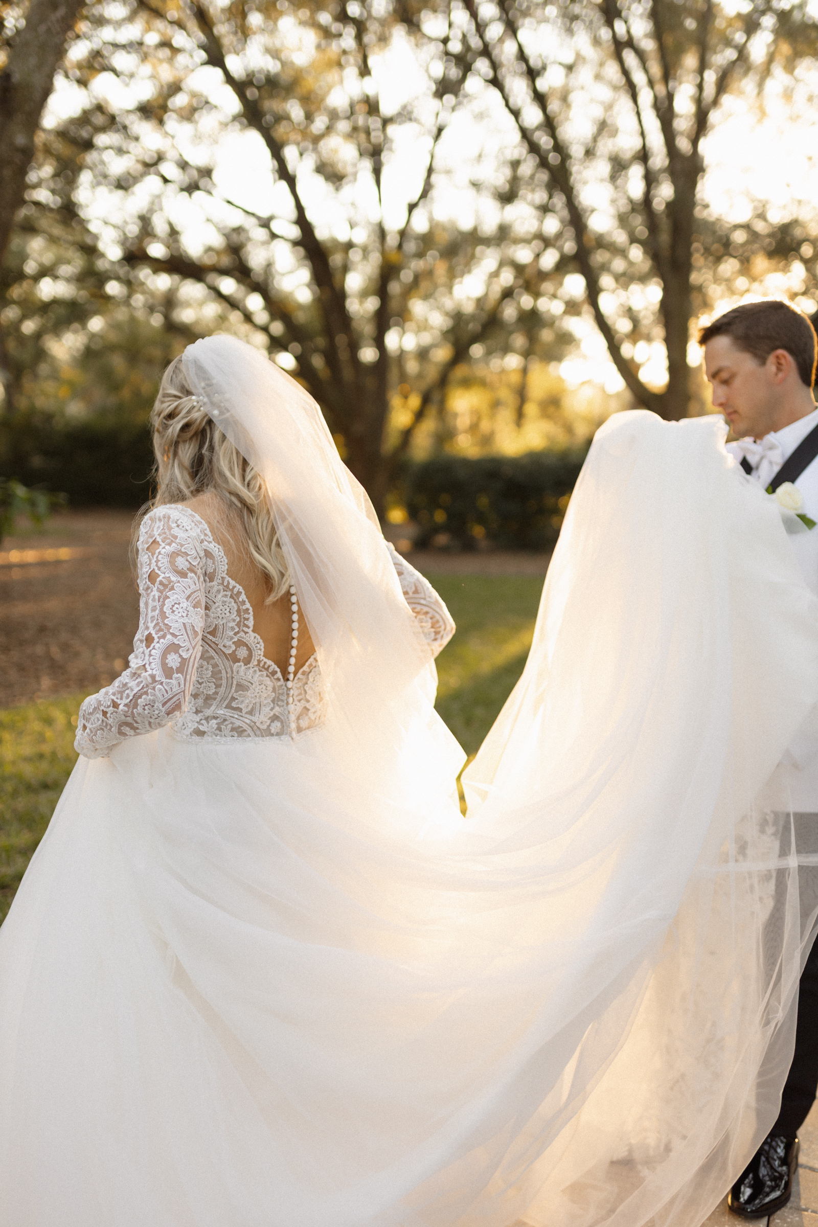 groom helps bride carry train at jacksonville fl wedding venue