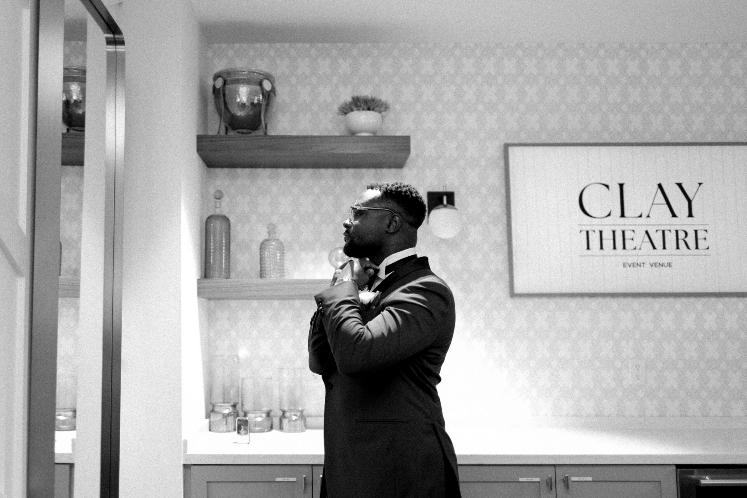 groom fixes tie in mirror at the clay theatre