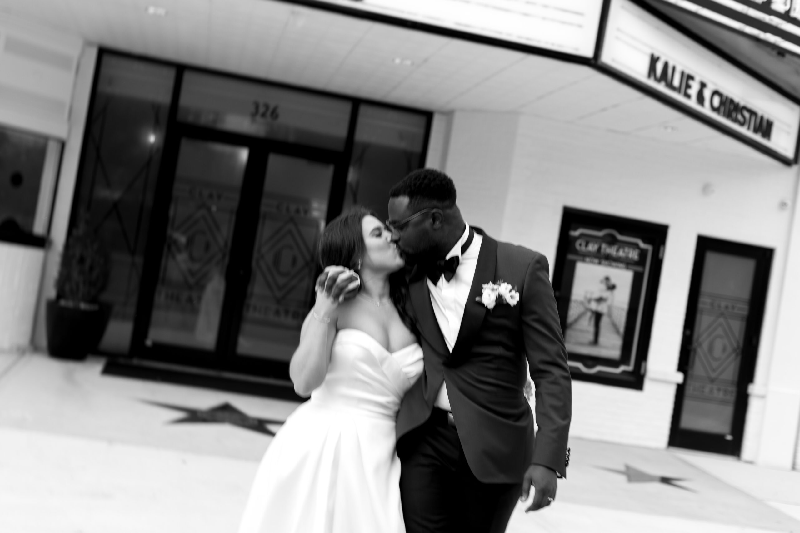 bride and groom kiss in front of the clay theatre wedding venue