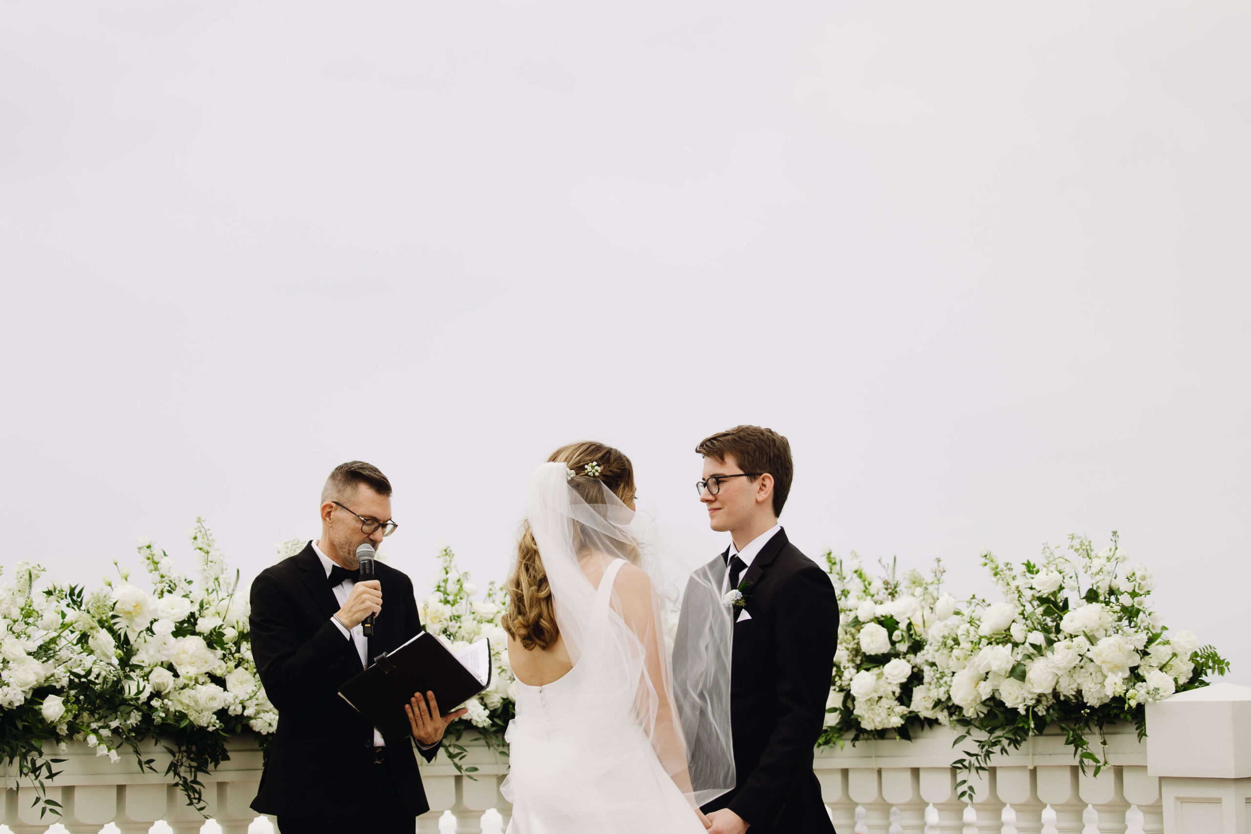 wide image of bride and groom standing with pastor
