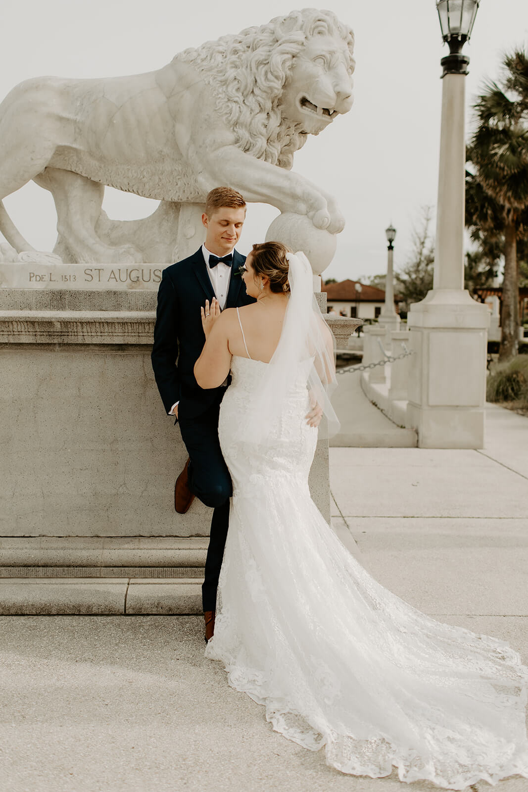 bride and groom stand together near bridge of lions in st augustine