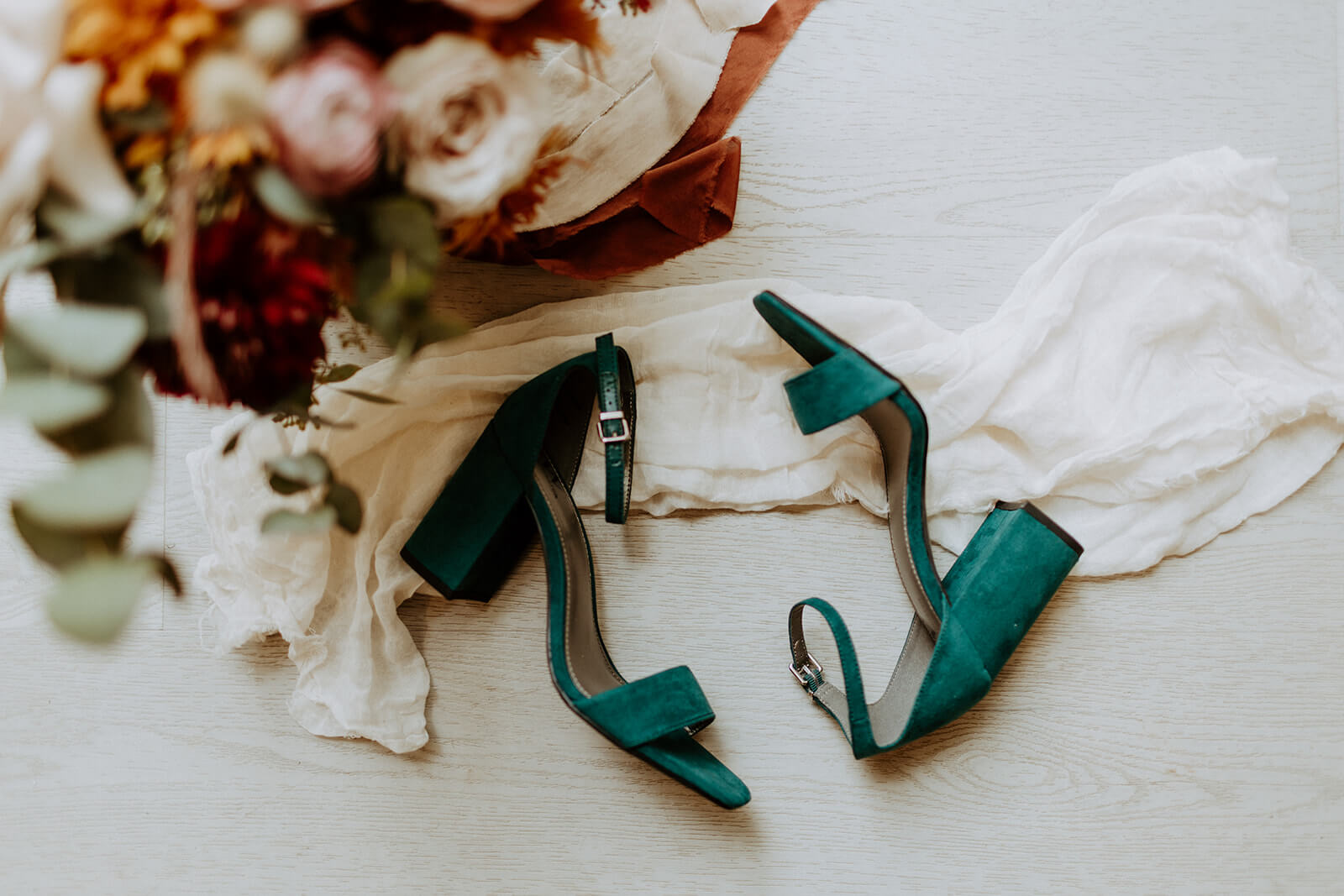 detail image of green velvet womans wedding shoes with floral arrangement