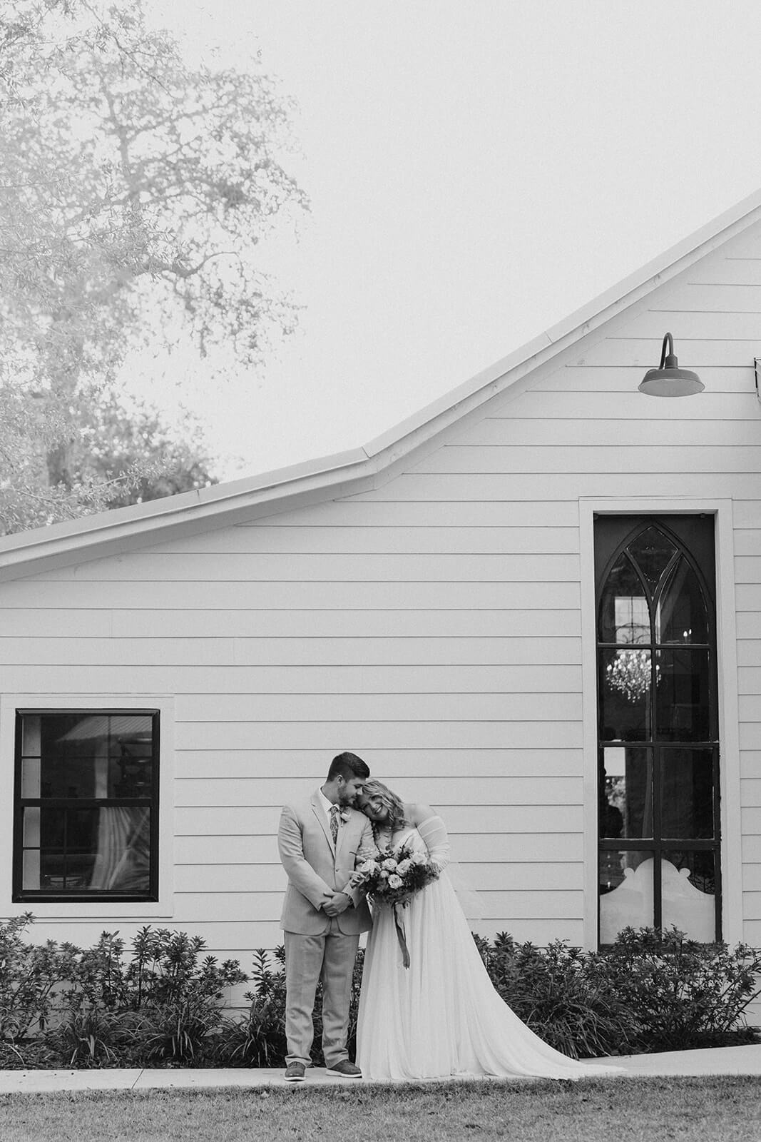 bride and groom stand together by chander oaks barn wedding venue