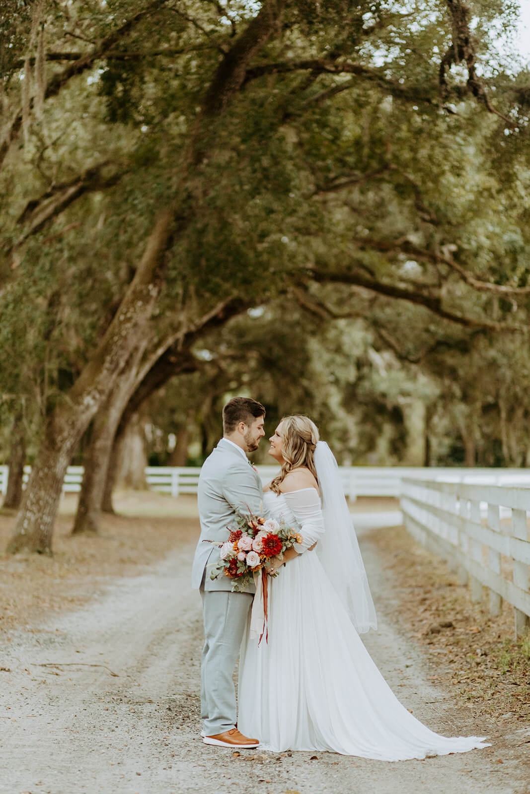 bride and groom standing together under large moss covered trees at wedding venue in jacksonville fl