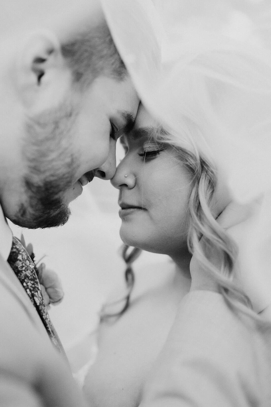 black and white image of stunning bride head to head under veil with husband