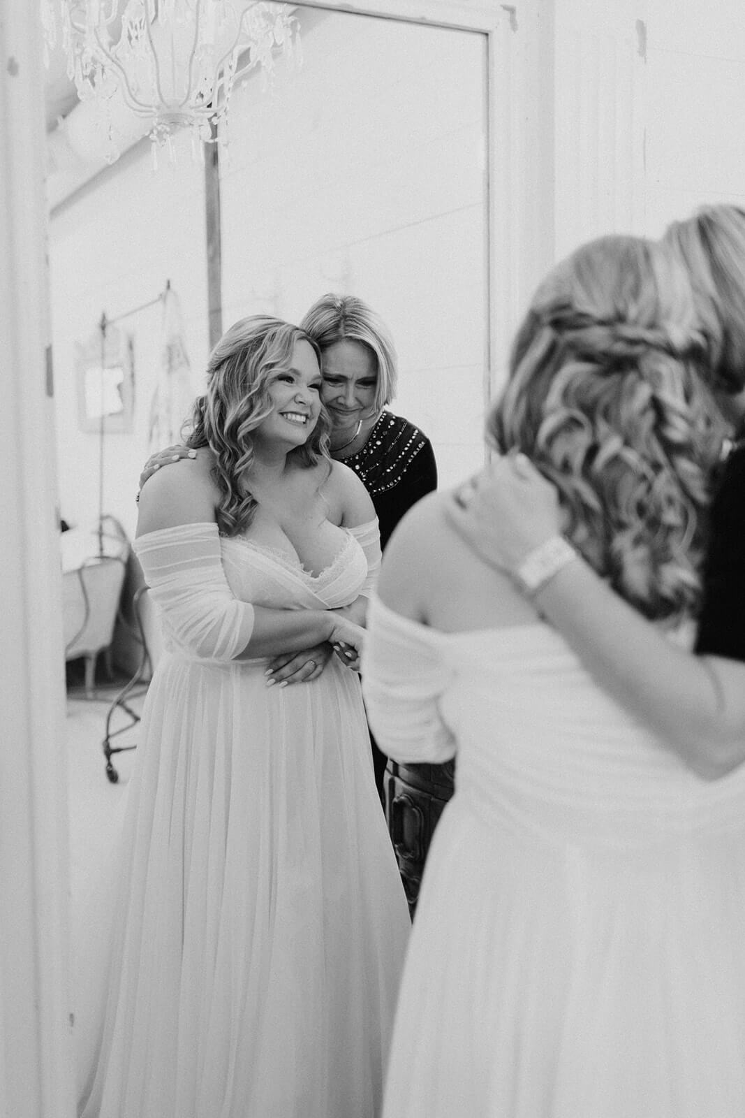 brides mom hugging her while they look into a mirror at chandler oaks barn in jacksonville fl