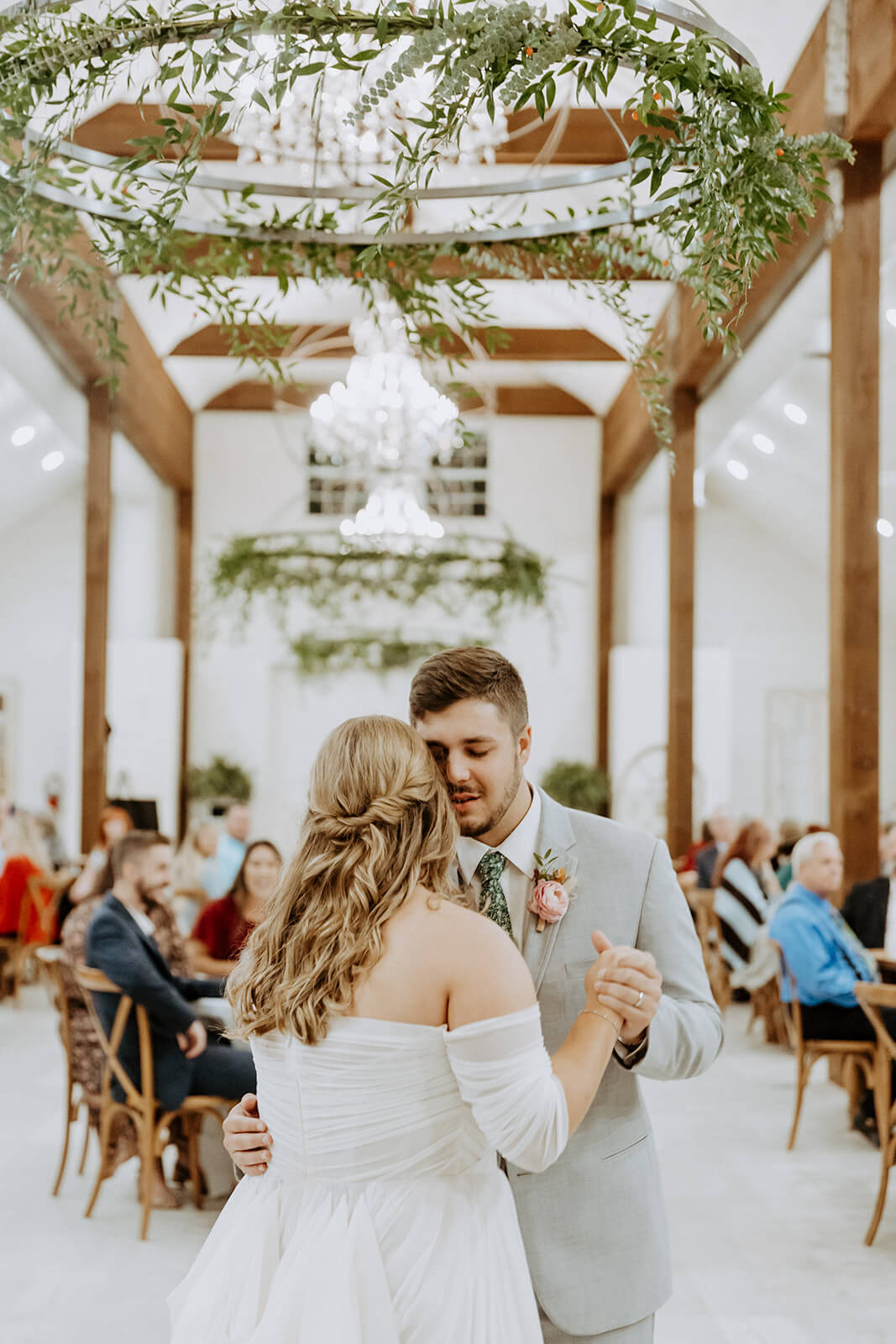 bride and groom have first dance in all white wedding barn