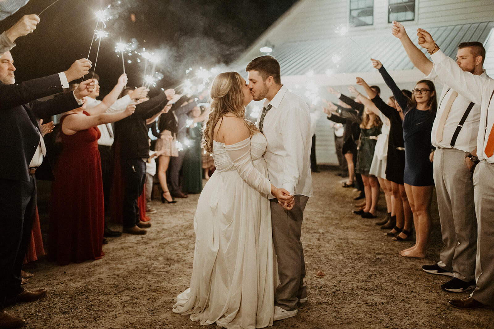 bride and groom kiss while they are surrounded by wedding guests with sparklers, taken by shandi lynn photo